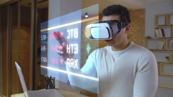 Человек в VR-наборе смотрит на виртуальный экран с финансовыми данными, живой репортаж, AR — стоковое видео