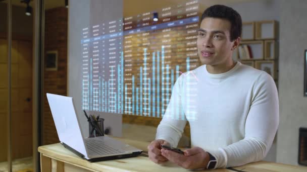 Joven asesor financiero mirando holograma de datos bursátiles, trabajando remotamente — Vídeo de stock