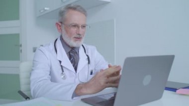 Kıdemli erkek doktor öğrencilere çevrimiçi bilgisayar ve tıbbi danışmanlık yoluyla öğretiyor.
