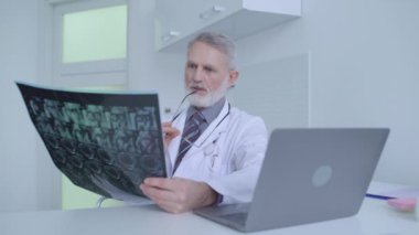 Düşünceli erkek doktor MRI taramasına bakıyor, teşhisi düşünüyor, ciddi hastalıklar.