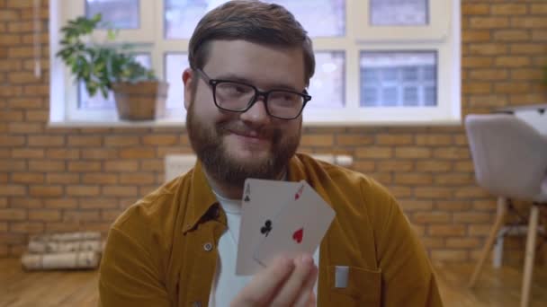 Радостный игрок в очках показывает пары тузов, держа фишки в руках — стоковое видео