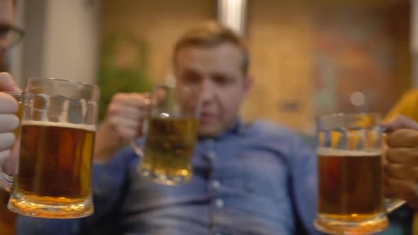 Jóvenes tintineando vasos de cerveza, fiesta masculina en casa, descansando un fin de semana — Vídeos de Stock