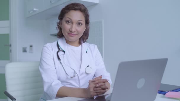 Confiada doctora hablando con el paciente, mirando a cam, servicios médicos — Vídeos de Stock