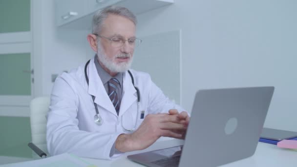 Мужской врач, имеющий конференц-связь с пациентом онлайн, медицинская консультация — стоковое видео