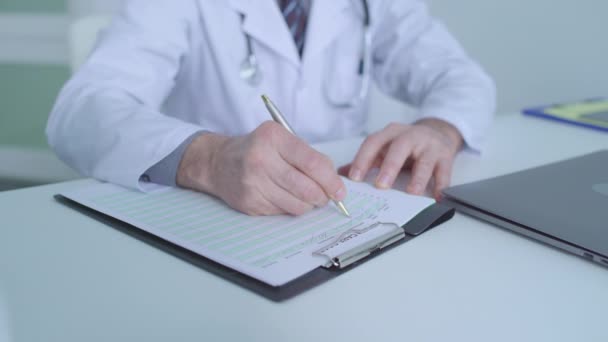 Чоловік-терапевт пише рекомендації щодо охорони здоров'я у пацієнтів медичного запису — стокове відео