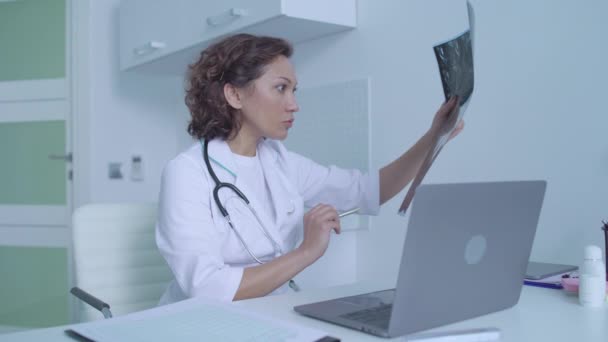 Σοβαρός ιατρός που ελέγχει τη μαγνητική τομογραφία, δακτυλογράφηση διάγνωση στο ηλεκτρονικό αρχείο υγείας — Αρχείο Βίντεο