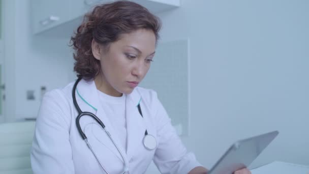 Занятая женщина-терапевт работает над таблетками, заполняет электронные медицинские записи — стоковое видео