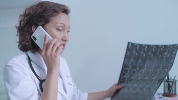 Serious woman doctor talking to patient by phone, informing about bad diagnosis — Stock Video