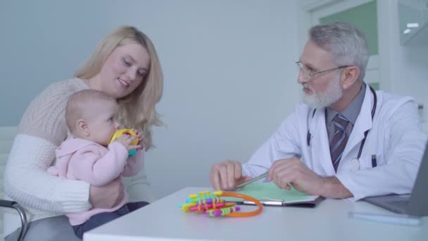 Jovem mãe e bebê bonito visitando médico de família na clínica, consulta de saúde — Vídeo de Stock