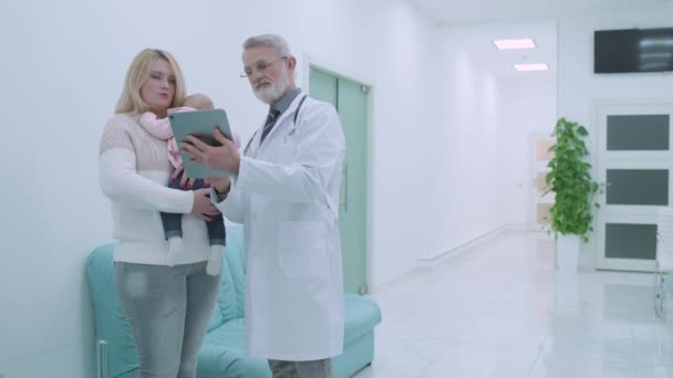 Junge Mutter, Kinderarzt spricht in Klinik, Arzt zeigt Testergebnisse auf Tabulator — Stockvideo