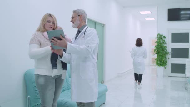 Rodinný lékař ukazující výsledky testu mladé matky na tabletě, rodinný lék — Stock video