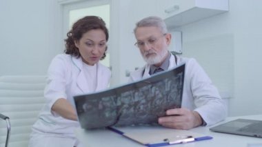 İki meslektaşım MRI taramasında yaralanma tedavisi ve takım çalışmasını tartışıyor.