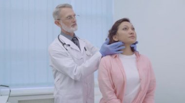 Erkek otolarolog hastanın boynunu muayene ediyor, hastanede check-up yaptırıyor, hastalık...