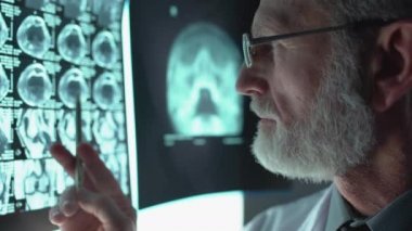 MR taraması yapan deneyimli bir tıp çalışanı. Test sonuçlarına, sağlık raporlarına bakıyor.