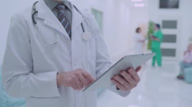 Erkek doktor, tablet uygulaması ve teknoloji kullanarak hastanın analizini internetten kontrol ediyor.