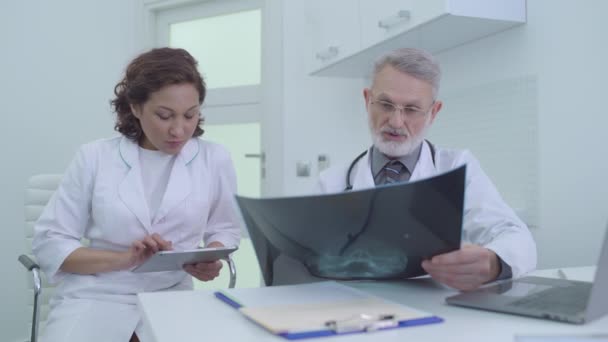 Traumatoloog controleert patiënten x-ray, verpleegkundige vullen elektronische medische dossiers — Stockvideo