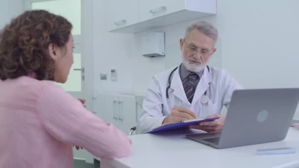 Vrouwelijke patiënt die ziektesymptomen aan de arts beschrijft en medische diensten ontvangt — Stockvideo