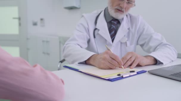 Médico sênior que escreve a prescrição e dando ao paciente, tratamento médico — Vídeo de Stock