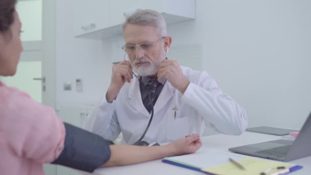 Médico que mede a pressão arterial do paciente, usando estetoscópio, check-up médico — Vídeo de Stock