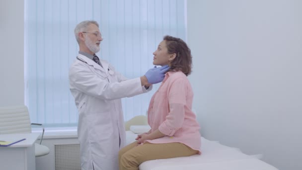 Otorrinolaringólogo en guantes revisando el cuello del paciente, síntoma de enfermedad, infección — Vídeo de stock