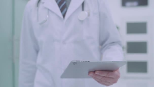 Médico varón con tabletas estrechando la mano de una colega en el hospital, trabajo en equipo — Vídeos de Stock