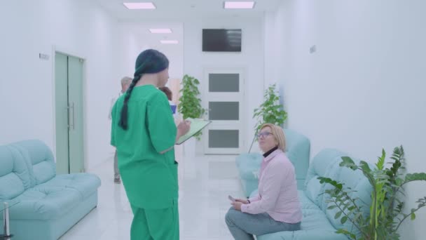 Enfermeira conversando com paciente na clínica, convidando para consulta médica, check-up — Vídeo de Stock