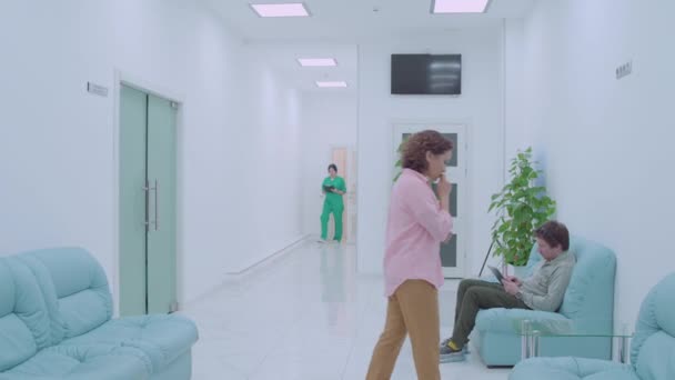 Nervózní žena čeká na zprávy na klinice, chirurg ujišťuje pacientovu matku — Stock video
