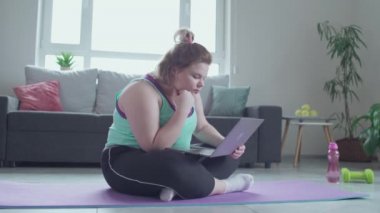 Aşırı kilolu bir kadın dizüstü bilgisayarda diyet bilgisi okuyor, kilo verme hedefi