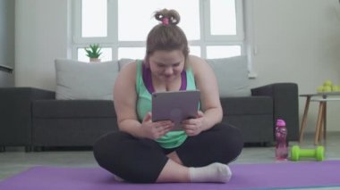 Heyecanlı tombul kız internette geziniyor, tablet sayfalarını izliyor, internetten rezervasyon yaptırıyor.