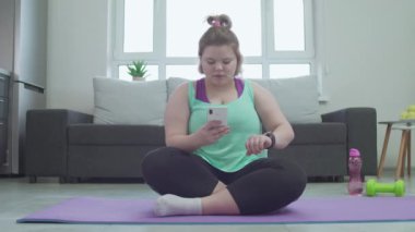 Genç bayan akıllı telefonu akıllı saatle senkronize ediyor, modern teknolojiyi kullanıyor.