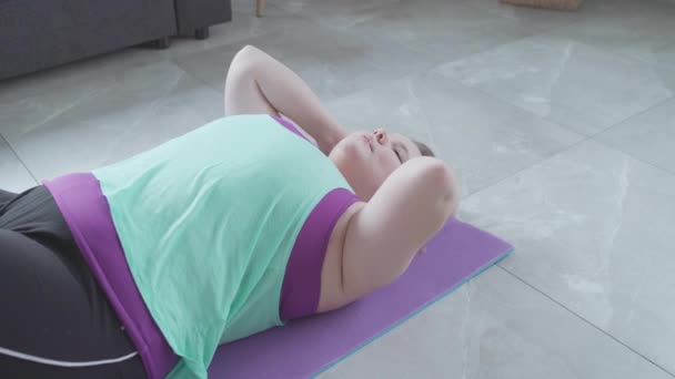 Grasso giovane donna che fa esercizio fisico sul pavimento per perdere grasso della pancia, sovrappeso — Video Stock