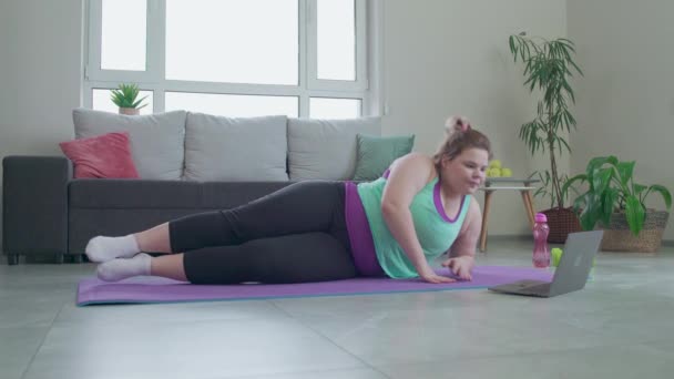 Mujer regordeta motivada viendo curso de entrenamiento deportivo en el ordenador portátil haciendo ejercicio en casa — Vídeos de Stock