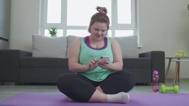 Молодая женщина с помощью приложения myger на смартфоне отправляет селфи другу — стоковое видео