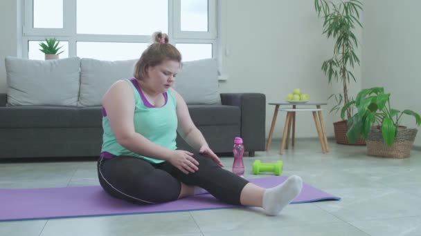 Mujer con sobrepeso haciendo ejercicio de estiramiento, sintiendo dolor agudo en la rodilla, trauma — Vídeos de Stock