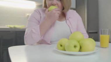 Genç bir kadın taze yeşil elma yiyor, bağışıklık sistemi için sağlıklı beslenmenin tadını çıkarıyor.