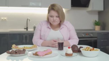Masadaki pasta ve pizzaya bakan düşünceli obez kadın, kilo kaybı.