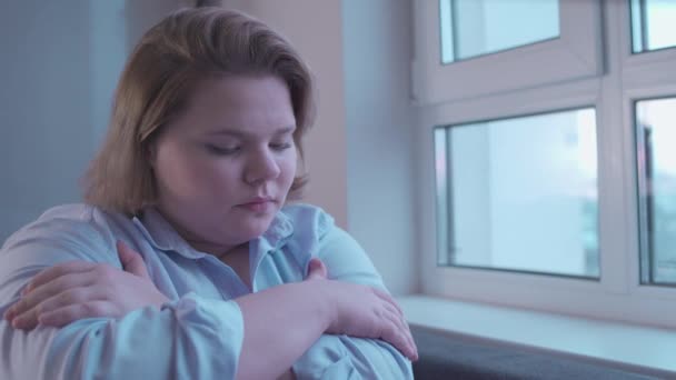 Sad plump girl looking in window, feeling depressed and lonely, insecurities — Stock Video