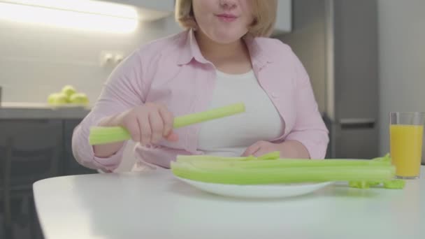 Плюс розмір жінки їсть селеру і усміхається, здорове харчування для схуднення — стокове відео