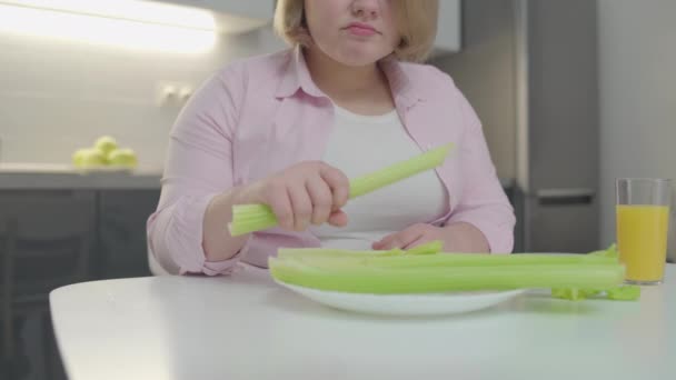 不快乐的肥胖女人咀嚼芹菜，不喜欢蔬菜饮食，体重减轻 — 图库视频影像