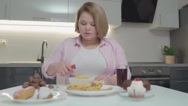 Mujer joven y regordeta añadiendo ketchup encima de papas fritas, comida rápida, calorías — Vídeo de stock