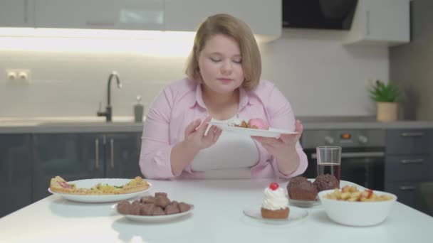 Placa de retención femenina joven regordeta con pasteles, disfrutando del postre, adicción al azúcar — Vídeo de stock
