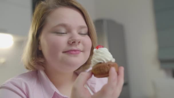 Heyecanlı obez kadın kremalı pasta yiyor, tatlı tatlı yiyor, yemek yiyor. — Stok video