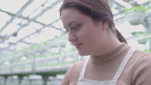 Молода жінка, що працює на виробництві рослин, усміхнене обличчя крупним планом, промисловість — стокове відео