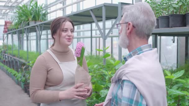 Trevlig kvinna som säljer blomkruka till nöjda kunder, framgångsrik växthusverksamhet — Stockvideo