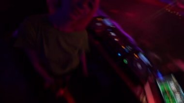 Pembe saçlı disk jokey kameraya bakıyor, DJ mikserinin yanında müzik dinliyor, rahatla.