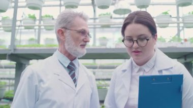 Erkek ve kadın bilim adamları ekin ekimi ve biyolojik araştırmayı tartışıyor.