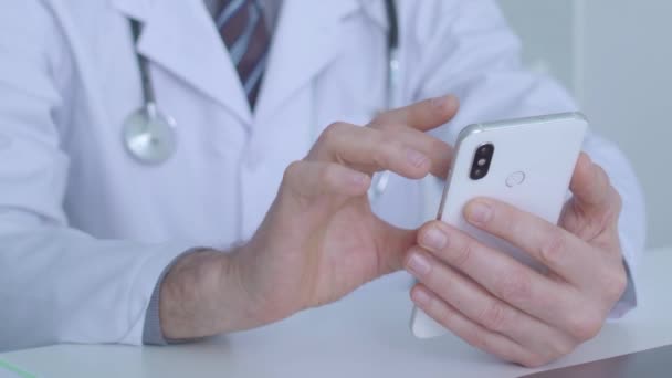 Doctor scrolling smartphone application, checking results of analysis online — Stock Video