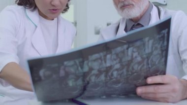 Tıbbi uzmanlardan oluşan bir ekip MRI görüntüsünü inceliyor, teşhisi tartışıyor, işbirliği yapıyor.