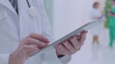 Erkek doktor tableti kaydırıyor, analizi kontrol ediyor, bilgi arıyor