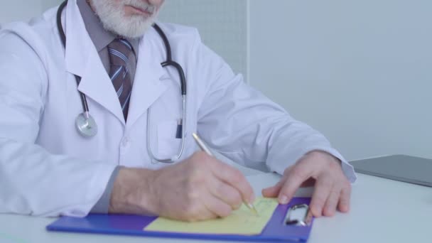 Trabajador de la clínica que escribe prescripción, sentado en la mesa, tratamiento médico, terapia — Vídeo de stock